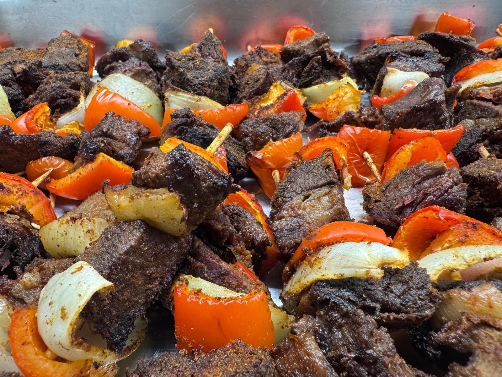 A tray of Jollof Republik beef suya skewers with red peppers and onions