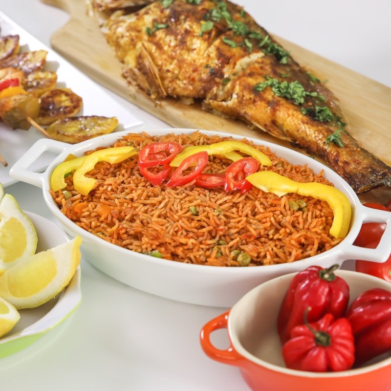 A dish of smoky Jollof rice with grilled fish and peppers